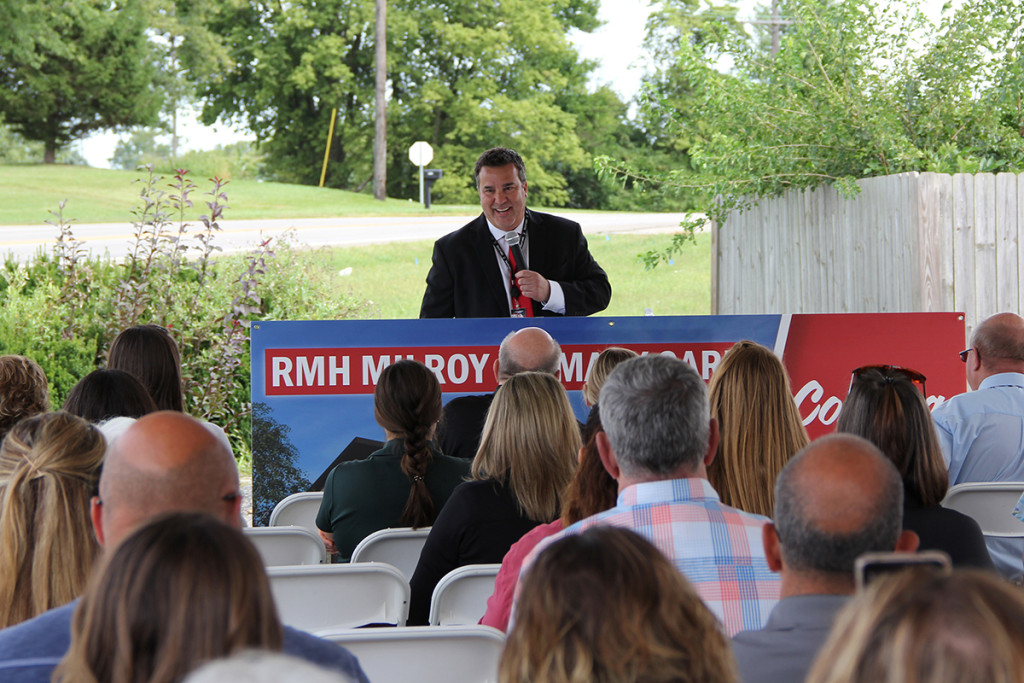 RMH CEO Brad Smith speaking at a podium.