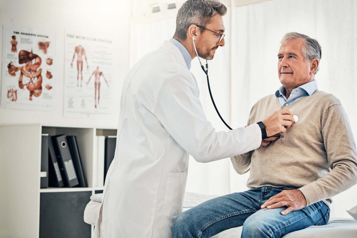Doctor listening to older man's heart